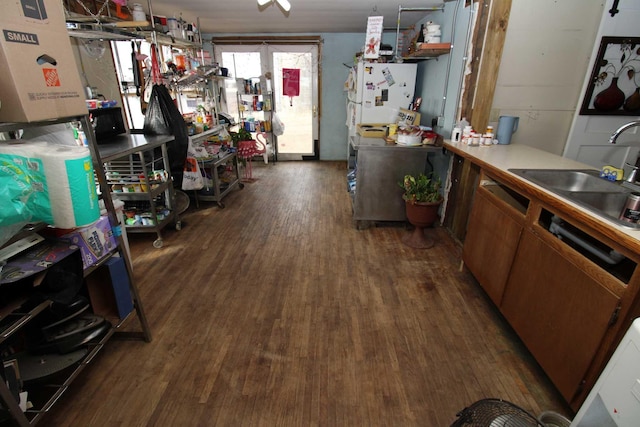 interior space featuring light countertops, wood finished floors, brown cabinets, a sink, and freestanding refrigerator