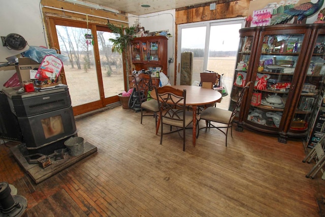 dining area with a healthy amount of sunlight, a wood stove, and hardwood / wood-style flooring