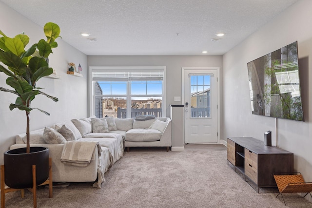 living area with recessed lighting, light carpet, a textured ceiling, and baseboards