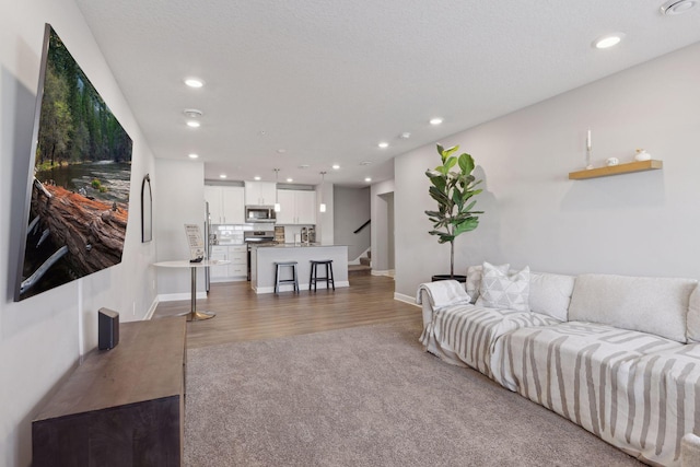 carpeted living area featuring stairs, baseboards, wood finished floors, and recessed lighting