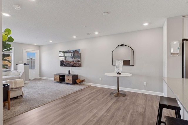 living room featuring a textured ceiling, baseboards, and wood finished floors