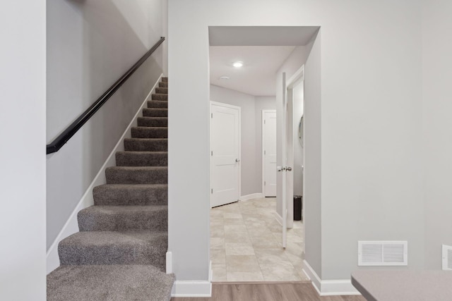 stairway with baseboards, visible vents, and wood finished floors