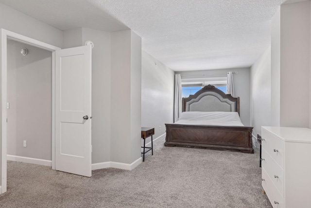 bedroom with light carpet, baseboards, and a textured ceiling