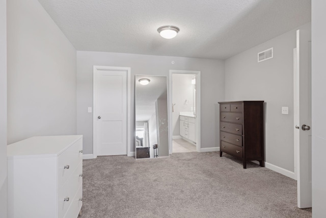 bedroom featuring visible vents, light carpet, connected bathroom, a textured ceiling, and baseboards