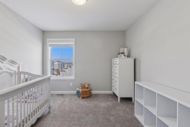 carpeted bedroom featuring a textured ceiling, a crib, and baseboards