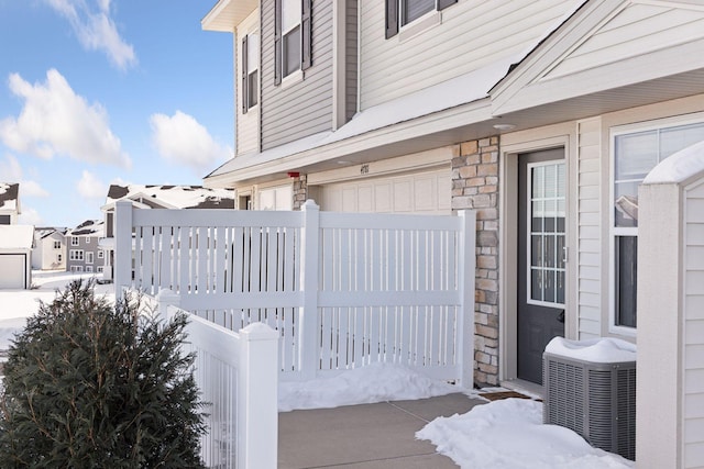 view of snow covered exterior with stone siding and central AC unit