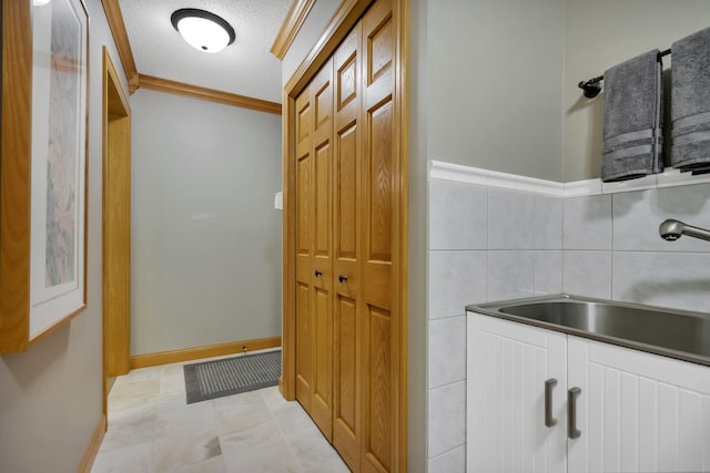 interior space with ornamental molding, sink, and a textured ceiling