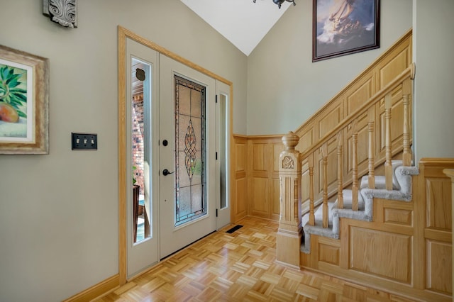 foyer entrance featuring high vaulted ceiling and light parquet flooring