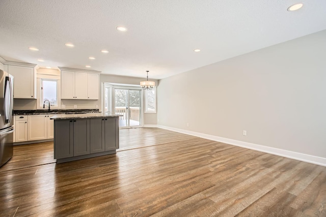 kitchen featuring pendant lighting, wood-type flooring, a center island, and sink