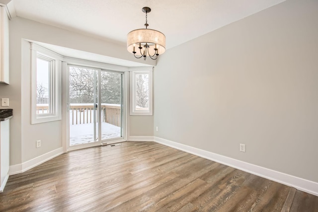 unfurnished dining area with dark hardwood / wood-style flooring and a notable chandelier