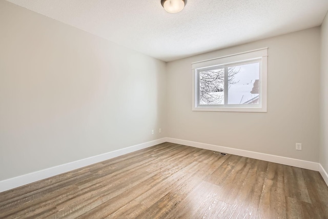 empty room featuring hardwood / wood-style flooring and a textured ceiling