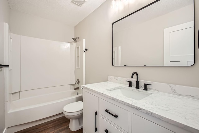 full bathroom with hardwood / wood-style floors, vanity, toilet, a textured ceiling, and washtub / shower combination