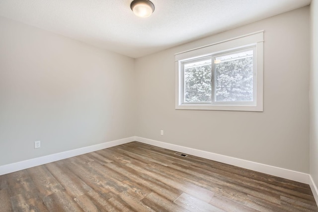 unfurnished room with dark hardwood / wood-style flooring and a textured ceiling