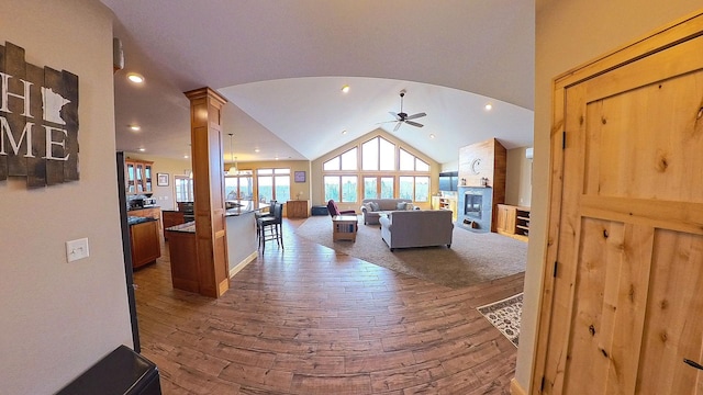 living area with arched walkways, wood-type flooring, a ceiling fan, and vaulted ceiling