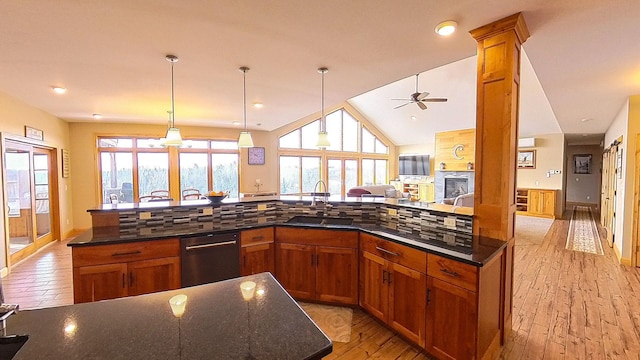 kitchen with a sink, dishwashing machine, brown cabinets, and a fireplace