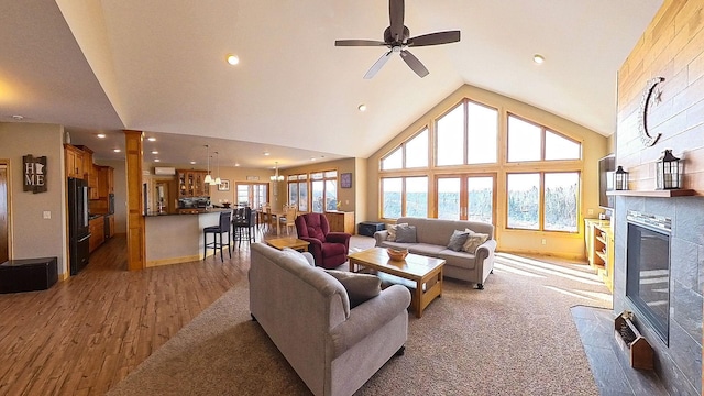 living room with high vaulted ceiling, a ceiling fan, wood finished floors, recessed lighting, and a tile fireplace