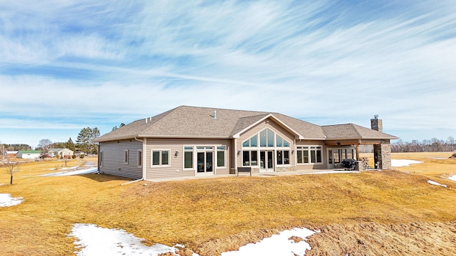 back of house featuring a yard, a shingled roof, a chimney, and a patio area