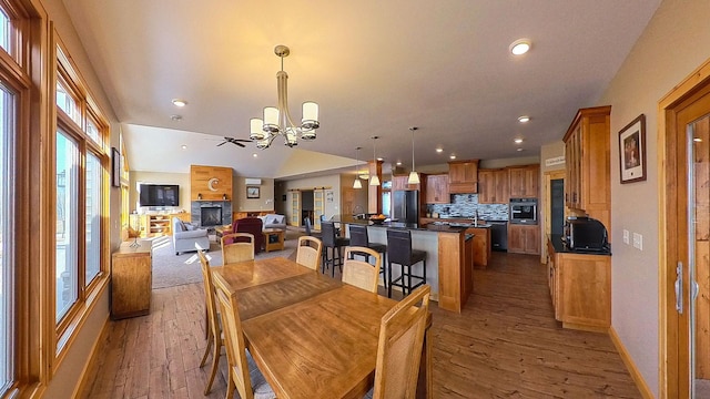 dining area with hardwood / wood-style floors, vaulted ceiling, a notable chandelier, and recessed lighting