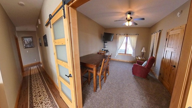 hallway featuring carpet flooring, baseboards, and a barn door