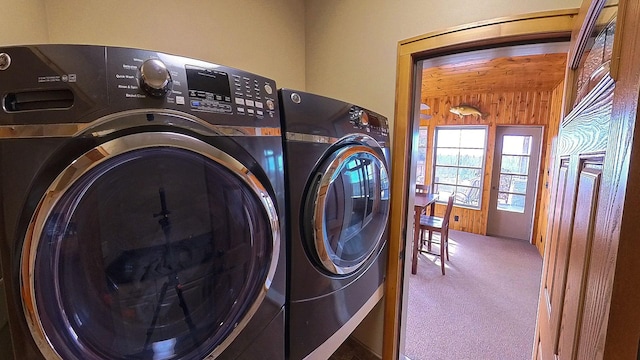 laundry room featuring carpet floors, wooden walls, laundry area, and washing machine and clothes dryer