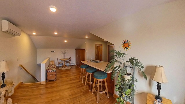 dining area featuring an AC wall unit, recessed lighting, light wood finished floors, and vaulted ceiling