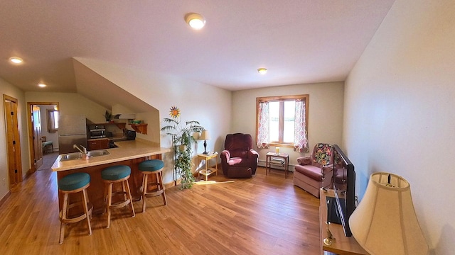 interior space featuring baseboards, light wood-type flooring, freestanding refrigerator, and a sink