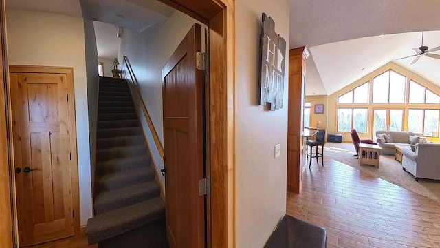 stairway with wood-type flooring, a ceiling fan, and vaulted ceiling