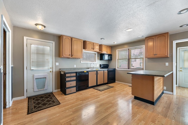 kitchen with light wood finished floors, baseboards, dark countertops, a breakfast bar area, and black appliances