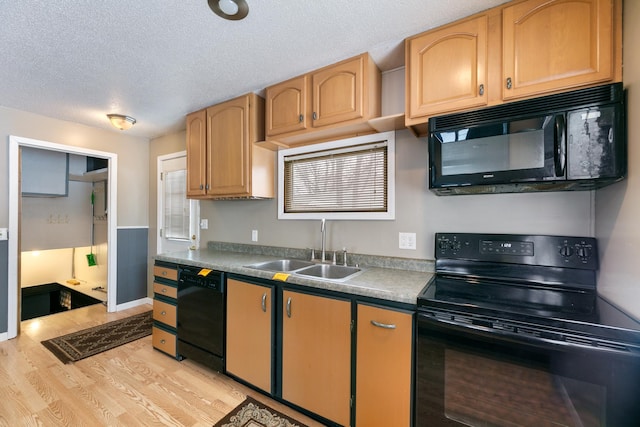 kitchen with baseboards, light wood-style flooring, a textured ceiling, black appliances, and a sink