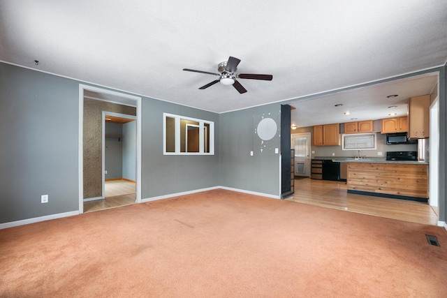 unfurnished living room with ceiling fan, light carpet, a sink, visible vents, and baseboards