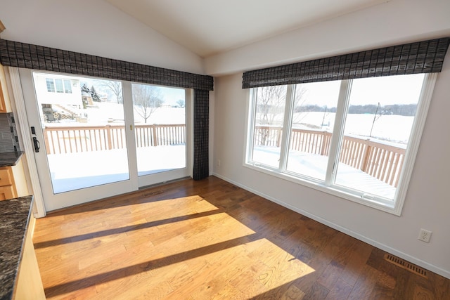 interior space featuring a water view, lofted ceiling, and dark hardwood / wood-style floors
