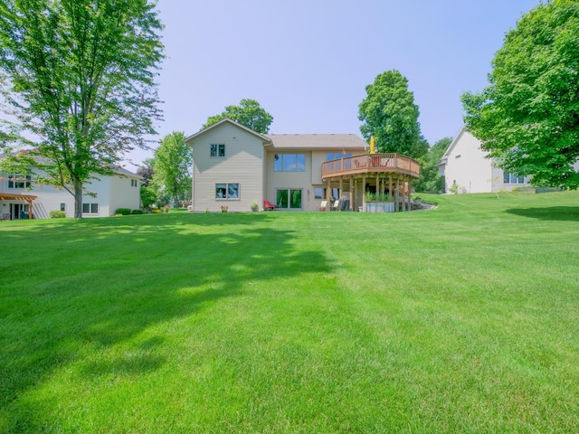 rear view of property with a wooden deck and a lawn