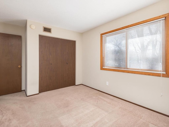 unfurnished bedroom with a closet and light colored carpet