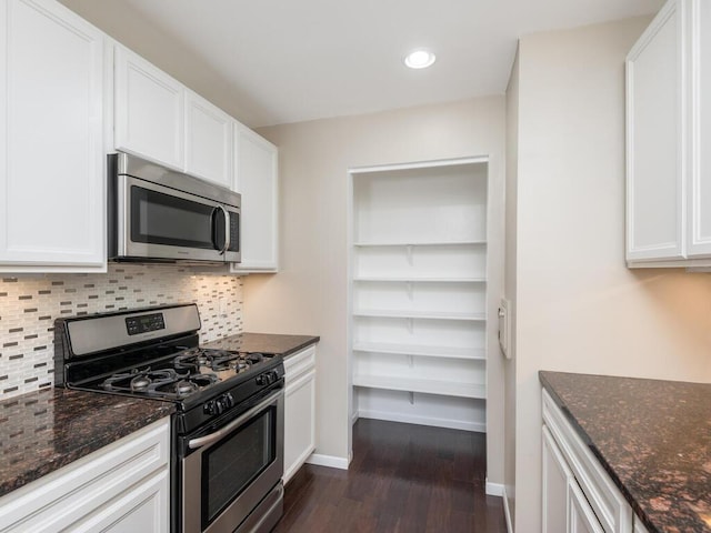 kitchen with appliances with stainless steel finishes, white cabinetry, and dark stone counters