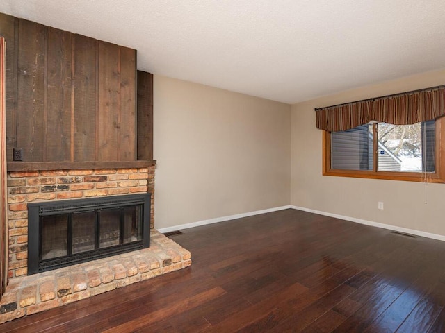 unfurnished living room with dark wood-type flooring and a brick fireplace