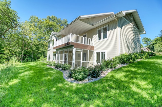 rear view of house with a balcony, a lawn, and a sunroom