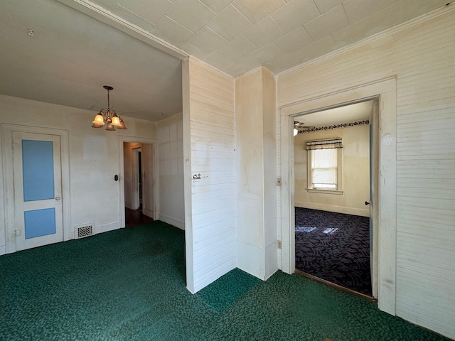 carpeted empty room featuring an inviting chandelier and visible vents