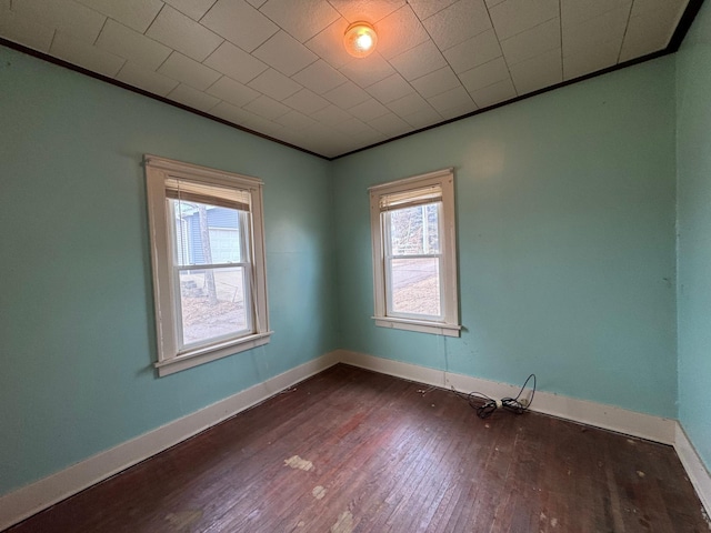 unfurnished room with baseboards, dark wood-type flooring, and crown molding