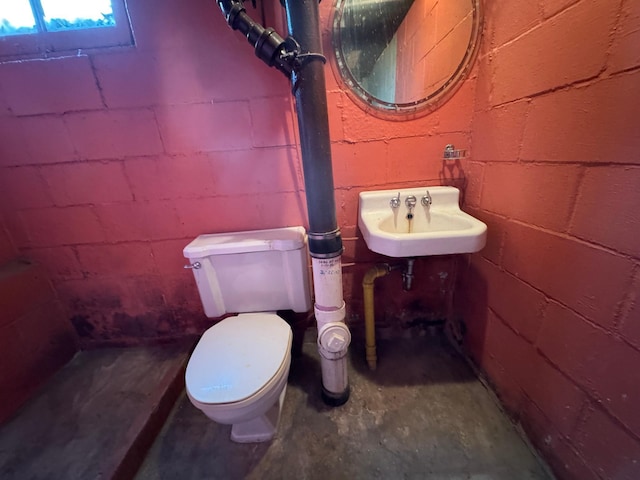 bathroom with toilet, unfinished concrete flooring, and a sink