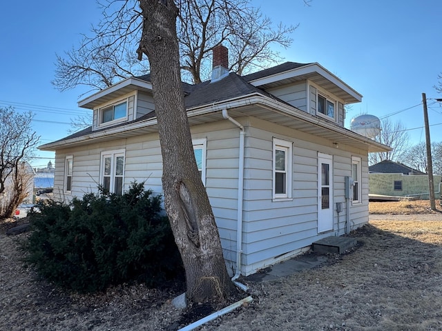 view of side of property featuring roof with shingles and a chimney