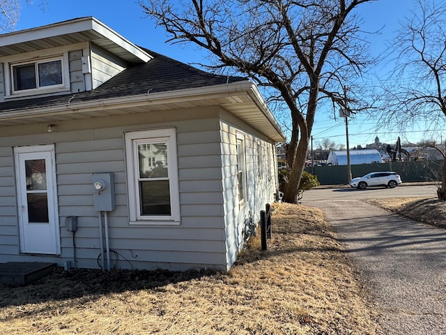 view of side of home with roof with shingles and driveway