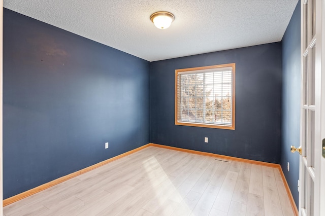 unfurnished room featuring a textured ceiling and light wood-type flooring