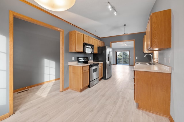 kitchen with rail lighting, appliances with stainless steel finishes, sink, and light hardwood / wood-style floors