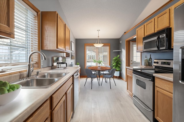 kitchen featuring sink, decorative light fixtures, a textured ceiling, appliances with stainless steel finishes, and light hardwood / wood-style floors