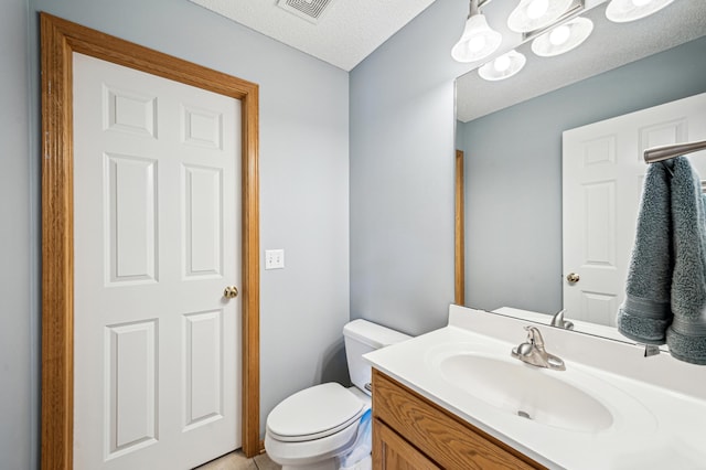 bathroom featuring vanity, a textured ceiling, and toilet