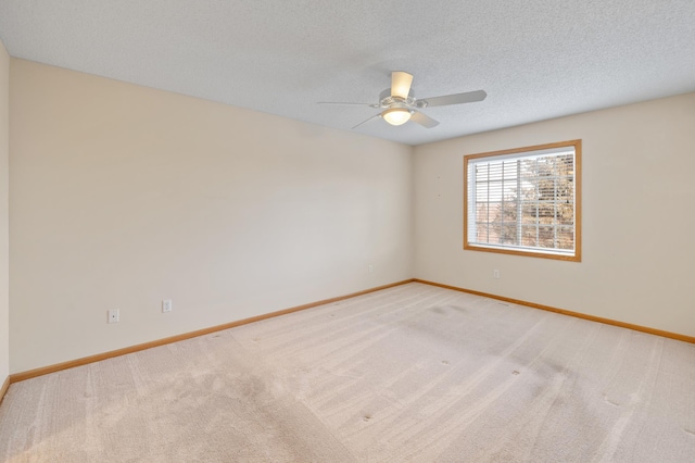 unfurnished room featuring ceiling fan, light colored carpet, and a textured ceiling