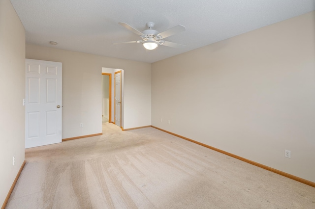 spare room with a textured ceiling, light colored carpet, and ceiling fan