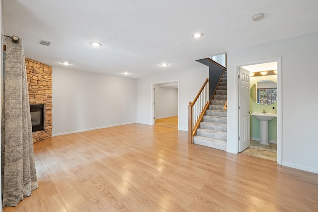 unfurnished living room with sink, a fireplace, and light hardwood / wood-style floors