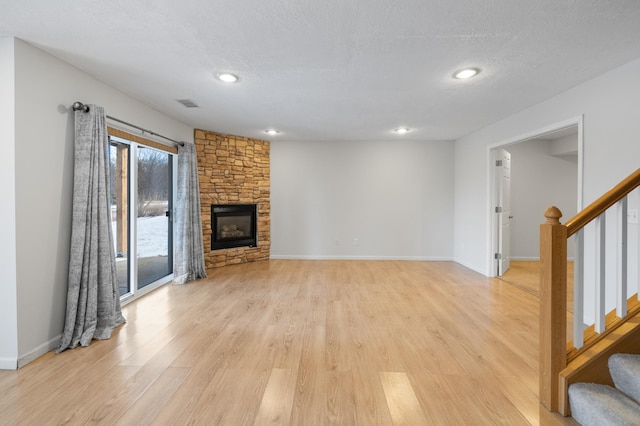 unfurnished living room with light wood-type flooring, a textured ceiling, and a fireplace