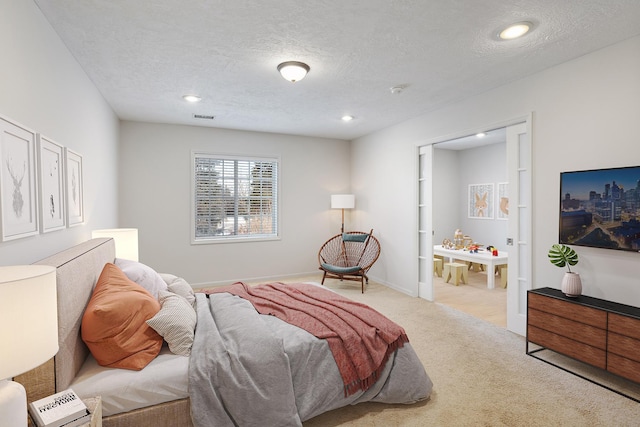 carpeted bedroom with ensuite bath and a textured ceiling